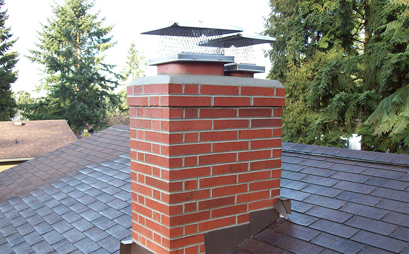 Chimney Rebuild & Repointing project in Scarborough — Rebuilt red brick chimney with new concrete crown and stainless rain cap on a shingled roof