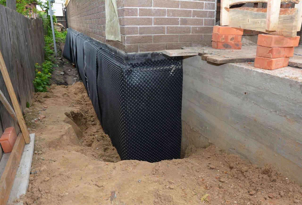 Exterior foundation wall excavated and wrapped with black dimple waterproofing membrane